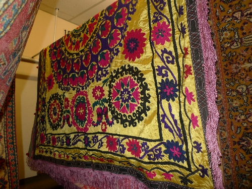 A Uzbekistan Suzanie wall hanging with silk frame fringe repeating stylized floral motifs 160cm x