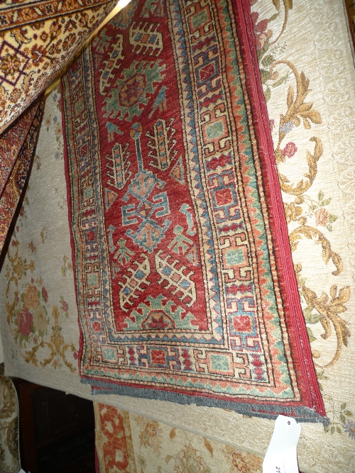 A Kazak runner with geometric motifs on a red field surrounded by running borders