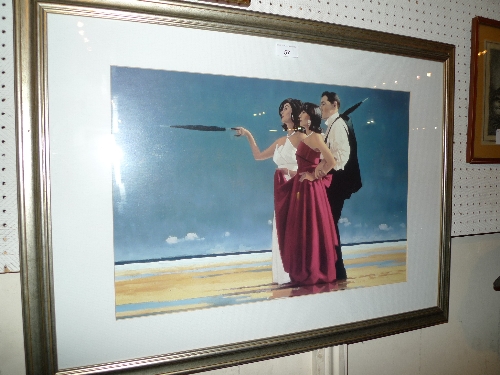 A Jack Vettriano print of a gentleman and two ladies on a beach in a silvered frame