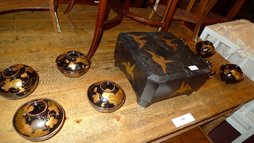 A set of eight C19th Japanese lacquered rice bowls with covers heightened in gilt and a similar