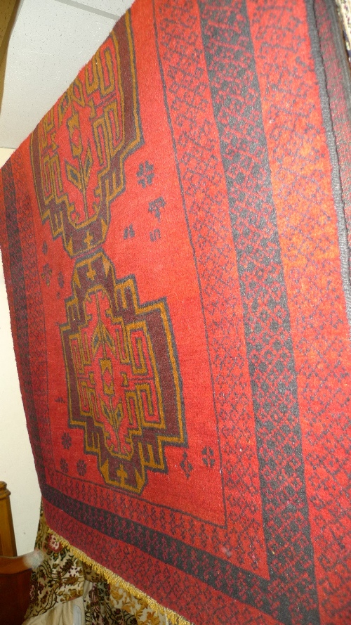 A hand knotted Persian Belouch rug the red field with bookcover design 205cm x 105cm