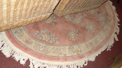 An oval Chinese rug with salmon pink field and floral decoration