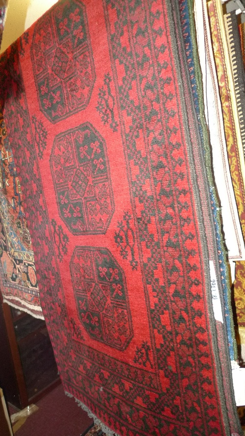 A hand knotted Afghan runner the red field with repeated motifs within a stylized border 280cm x