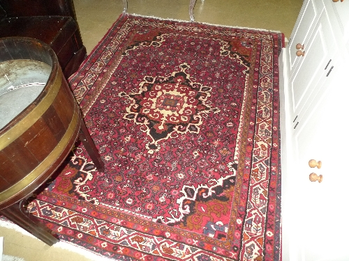 A hand knotted Persian Havandan rug the red ground with central medallion