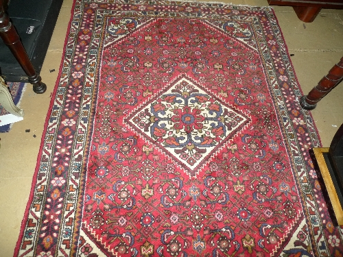 A hand knotted Hunnador rug red fields central diamond pendant multi border