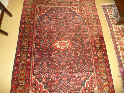 A hand knotted Persian rug the red ground with allover stylized decoration