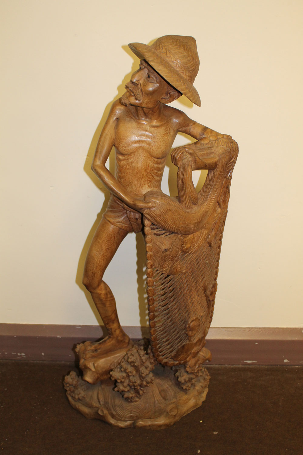 A CARVED HARDWOOD SCULPTURE, in exotic hardwood, depicting a bearded fisherman with net, wearing