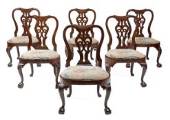 A set of six George II red walnut chairs, circa 1740, each H-shaped back centred by a pierced vase