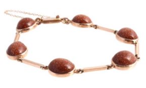 A glass goldstone bracelet, the oval cabochon glass goldstones linked by polished bars, the clasp
