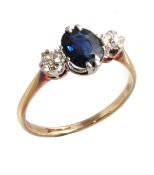 A sapphire and diamond ring, the central oval cut sapphire in claw settings between two brilliant