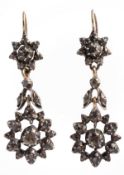 A pair of diamond earpendents, the flower head drops with articulated stems and star shaped