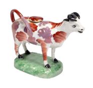 A British pearlware cow-creamer, possibly Cambrian Pottery, painted with iron-red and pink-lustre