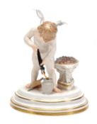 A Meissen figure of Cupid, modelled forging an arrow, 16cm high, incised M143, blue crossed swords