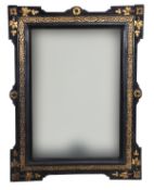 A French ebonised and gold painted mirror, 20th century, with outset corners, gilt trailing