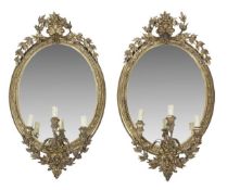 A pair of Victorian gilt composition framed three light girandoles, late 19th century, of oval