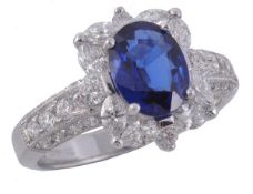 An 18 carat gold sapphire and diamond cluster ring, the oval cut sapphire within a surround of