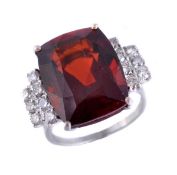 A garnet and diamond dress ring, the cushion cut garnet between brilliant cut diamond set