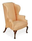 A George II mahogany framed and upholstered wing armchair, circa 1740, padded back, outswept arms,