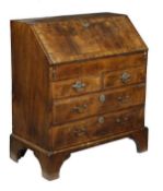 A George II walnut and featherbanded bureau, circa 1740, the fall opening to drawers, pigeon holes