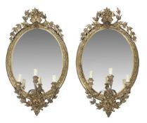 A pair of Victorian gilt composition framed three lights girandoles, late 19th century, of oval