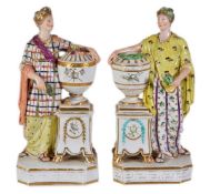 A pair of Derby classical maidens emblematic of Peace and Plenty, modelled standing beside urns,