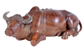 A South East Asian carved and stained hardwood model of a recumbent water buffalo, naturalistically