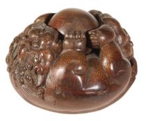 A Chinese bamboo carving of a curling lion dog holding a ball within its four paws, 10cm diameter