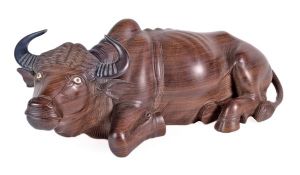 A South East Asian carved and stained hardwood model of a recumbent water buffalo, with inset bone