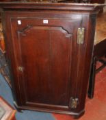 A 18th century oak corner cupboard enclosed by an arched panelled door, 80cm