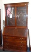 A George III style mahogany bureau cabinet with dentil cornice above astragal glazed doors, the