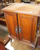 An Edwardian mahogany fold over top table and an oak two door panelled cupboard