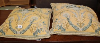 A pair of cream and yellow cushions with urns. Three silk gold coloured cushions. A pair of woven