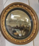 A giltwood convex wall mirror in Regency style, convex mirror plate, reeded ebonised moulding,