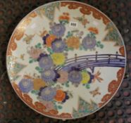 An early 20th century Imari charger painted with flowers and insects, the base with stilt marks,