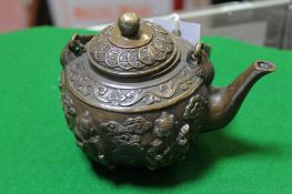A Chinese brass teapot decorated with coins and figures; approximately 11cm high