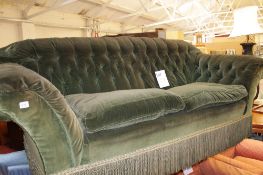 A green velvet upholstered sofa, late 19th/ early 20th century, arched and buttoned rectangular