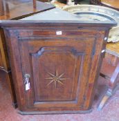 A late 18th century oak and parquetry hanging corner cupboard