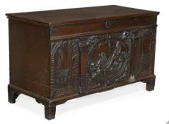 A Charles II cedar chest, circa 1660, hinged top, front panel carved with a central scene of