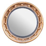 A giltwood framed circular wall mirror in Regency style, 19th century, with convex plate within a