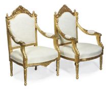 A pair of Continental carved giltwood armchairs, 18th century and later, carved throughout with