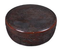 A Japanese lacquered wood box and cover of circular form intricately carved with a central panel