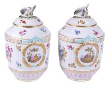 A pair of German porcelain Berlin style ovoid vases and covers, with eagle finials, painted with