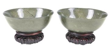 A pair of Chinese spinach jade circular bowls with slightly flaring rims, the thinly carved stone