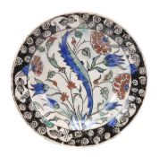 An Iznik pottery dish with a sloping rim and deep cavetto standing on a wide recessed foot, the