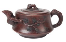 A Chinese Yixing teapot carved with designs of prunus flowers and butterflies, the handle and spout