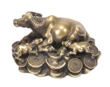 A Chinese bronze model of a reclining water buffalo, lying atop a pile of cash with its two