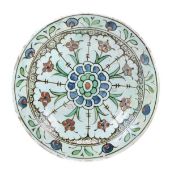 An Iznik pottery dish with a sloping rim and deep cavetto standing on a wide recessed foot, finely