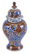 A Delft baluster vase and cover, painted in blue with flowers, reserved on a brown ground, 27cm