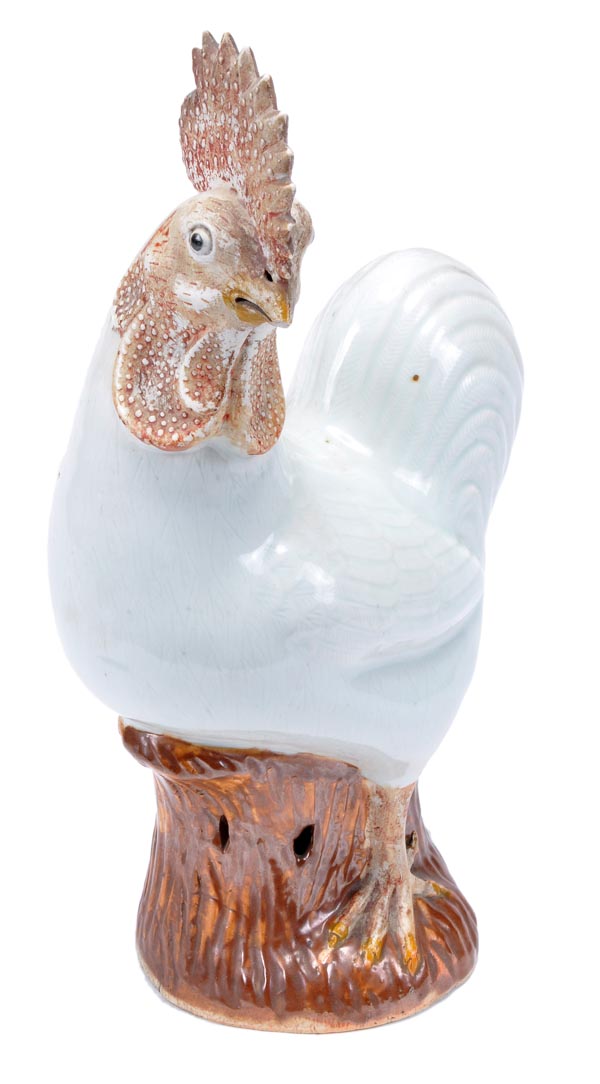 A Chinese Export figure of a cockerel, standing astride a tree stump with its head turned to its
