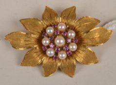A cultured pearl and ruby set flower brooch, the engraved open petals enclosing a cluster of eight